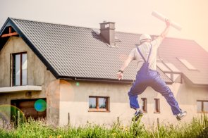 Bauen Fotografie eines Bauherren, der vor seinem Rohbau einen Luftsprung macht