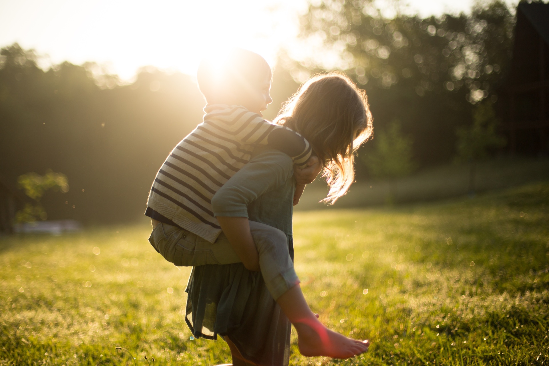 Kinder /Jugend Fotografie eines Kindes, welches ein kleineres auf dem Rücken Huckepack trägt