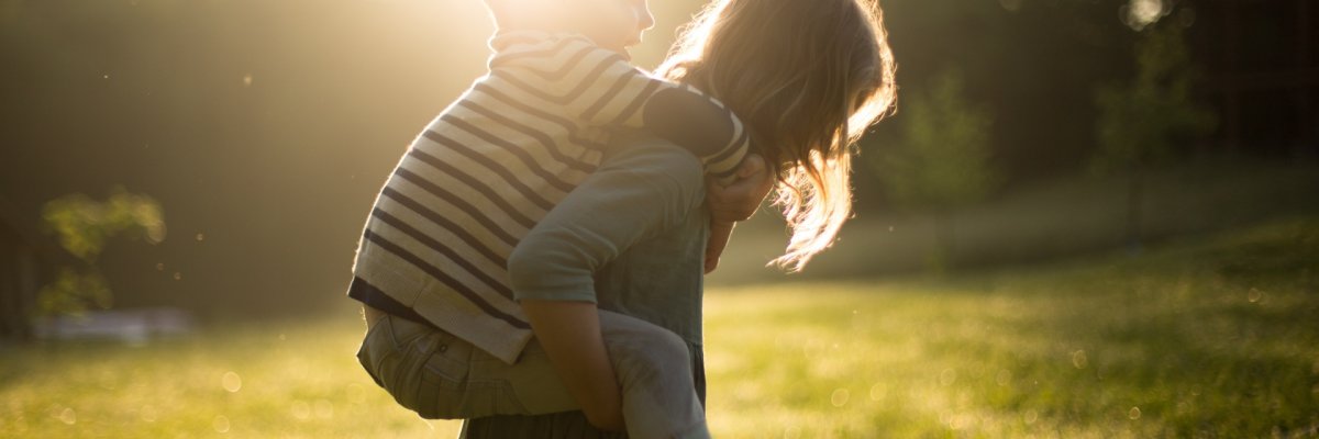 Kinder /Jugend Fotografie eines Kindes, welches ein kleineres auf dem Rücken Huckepack trägt