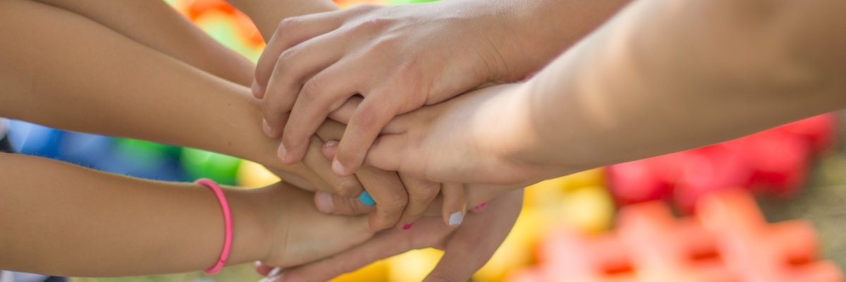 Fotografie zeigt mehrere Hände, die zusammmenhalten