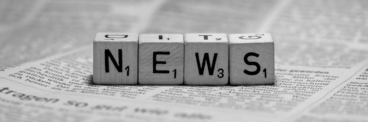 Würfel mit den Buchstaben N, E, W und S auf einer Zeitung liegend