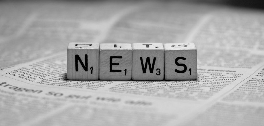 Würfel mit den Buchstaben N, E, W und S auf einer Zeitung liegend