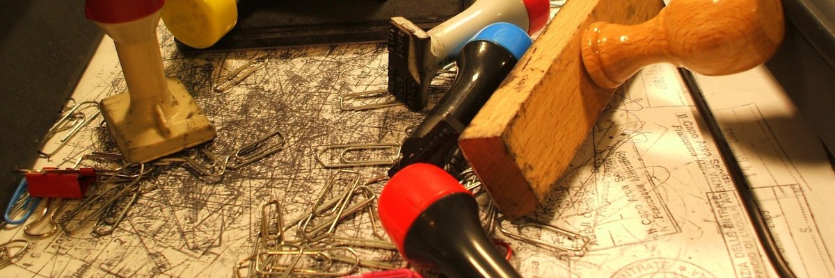 Verschiedene Stempel, ein Stempelkissen und Büroklammern auf einem Schreibtisch