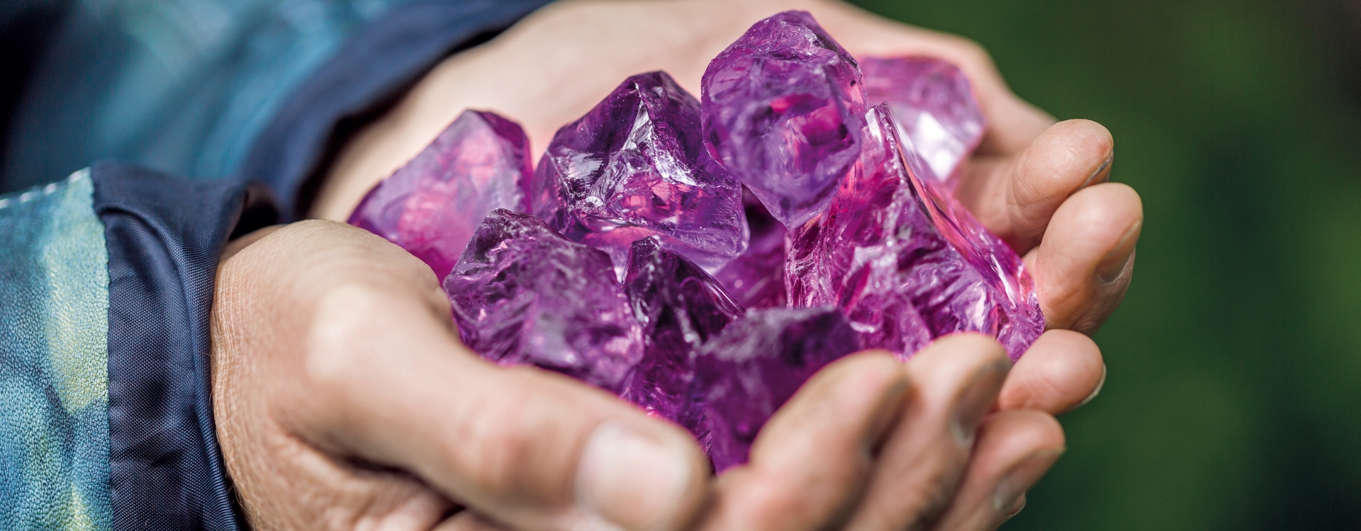 Zwei Hände mit darinliegenden lilafarbenen Edelsteinen
