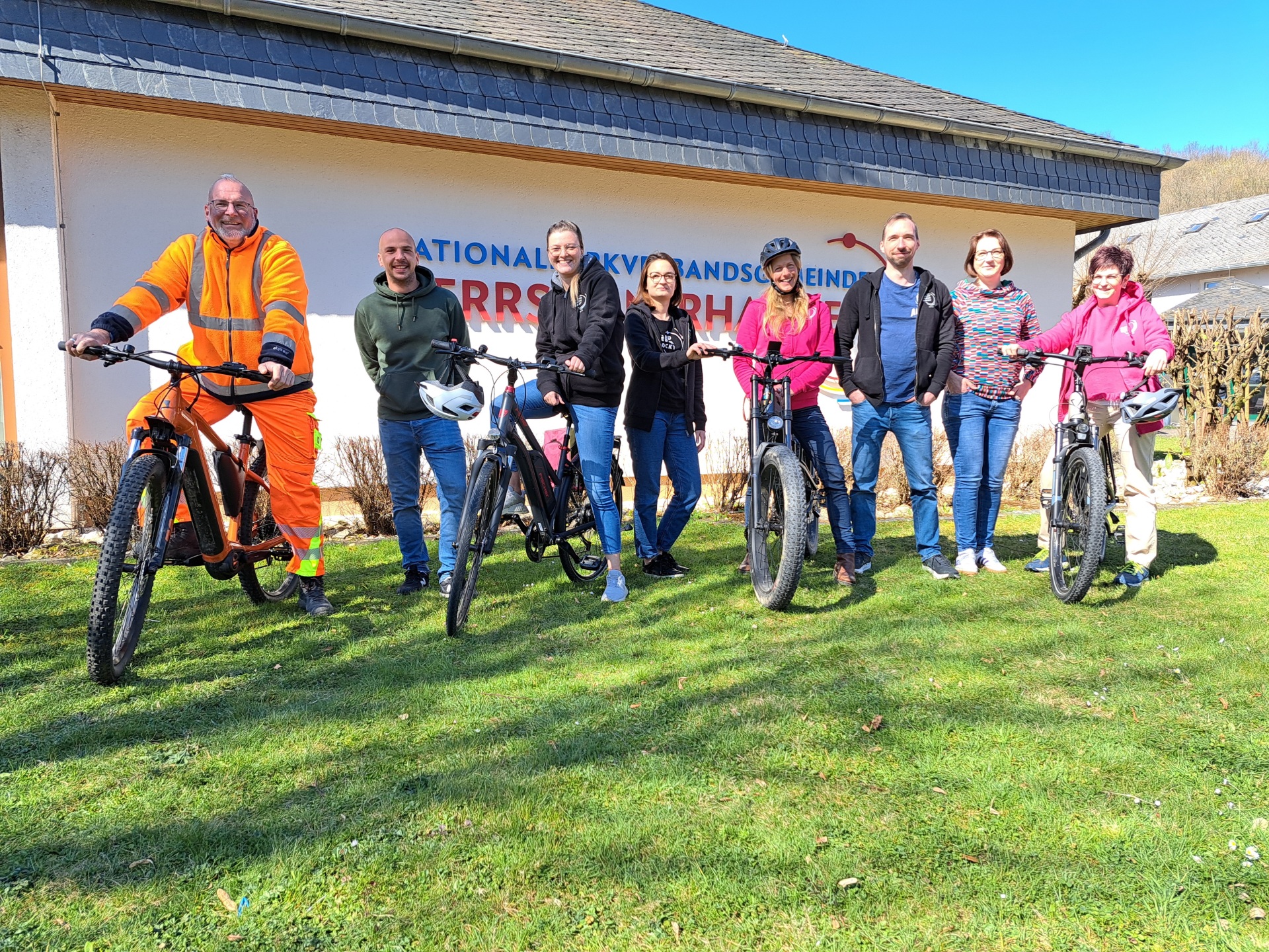 8 Personen, davon 3 Männer und 5 Frauen stehen mit 4 Fahrrädern vor dem Verbandsgemeindegebäude