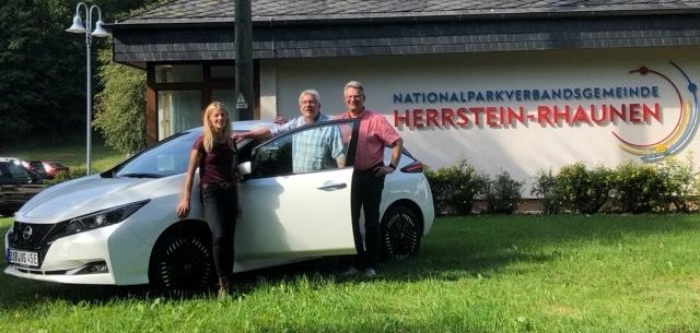 Foto von E-Bürgerauto vor dem Verwaltungsgebäude mit 3 Personen