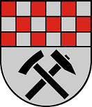 Schild schräglinks geteilt, vorne in schwarz schräggekreuzt je ein silberner Hammer und Schlegel, belegt mit einer silbernen Grubenlampe, hinten rot-silbern geschacht, belegt mit einem schwarzen Dreiberg.