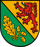 Schild schrägrechts geteilt, rechts in Grün ein goldenes Eichenblatt und 3 goldene Eicheln, links in Gold ein blaubewehrter und -gezungter roter Löwe.
