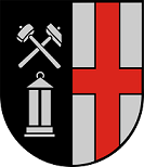Schild gespalten, vorne in Schwarz schräggekreuzt ein silberner Hammer und ein silberner Schlegel, darunter eine silberne Grubenlampe; hinten in Silber ein rotes Kreuz.