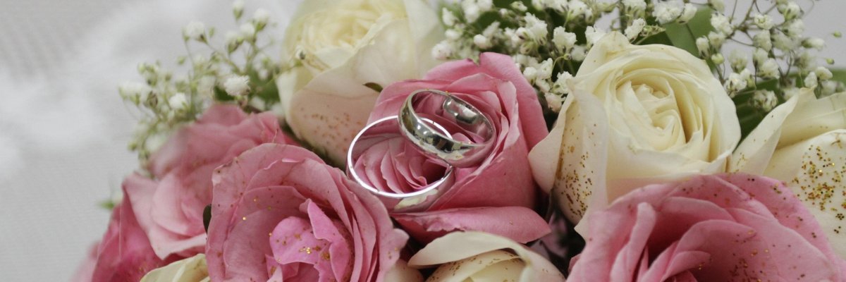 Brautstrauß mit Trauringen Brautstrauß aus weißen und rosanen Rosen mit 2 goldenen Trauringen daraufliegend