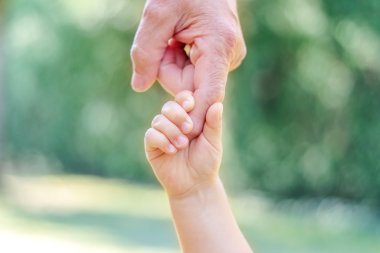 Großvater und Enkel halten Händchen. Kleine Kinderhand hält den großen Finger seines alten Vaters. Familienbande verschiedener Generationen. Konzept von Liebe, Fürsorge und Vertrauen.