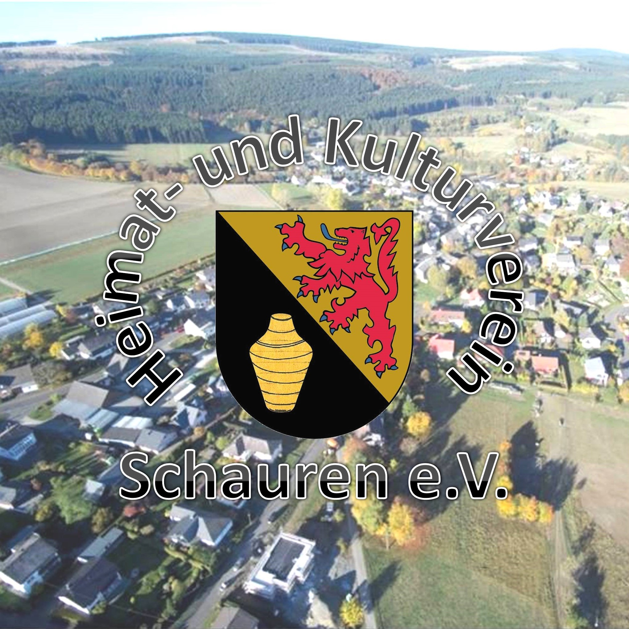 Luftaufnahme der Ortslage Schauren, in der Mitte das Wappen der OG, linke Hälfte gelber Krug auf schwarzem Hintergrund, rechte Hälfte rotes Tier auf gelbem Hintergrund, das Wappen wird umrahmt vom Schriftzug Heimat- und Kulturverein Schauren e.V.