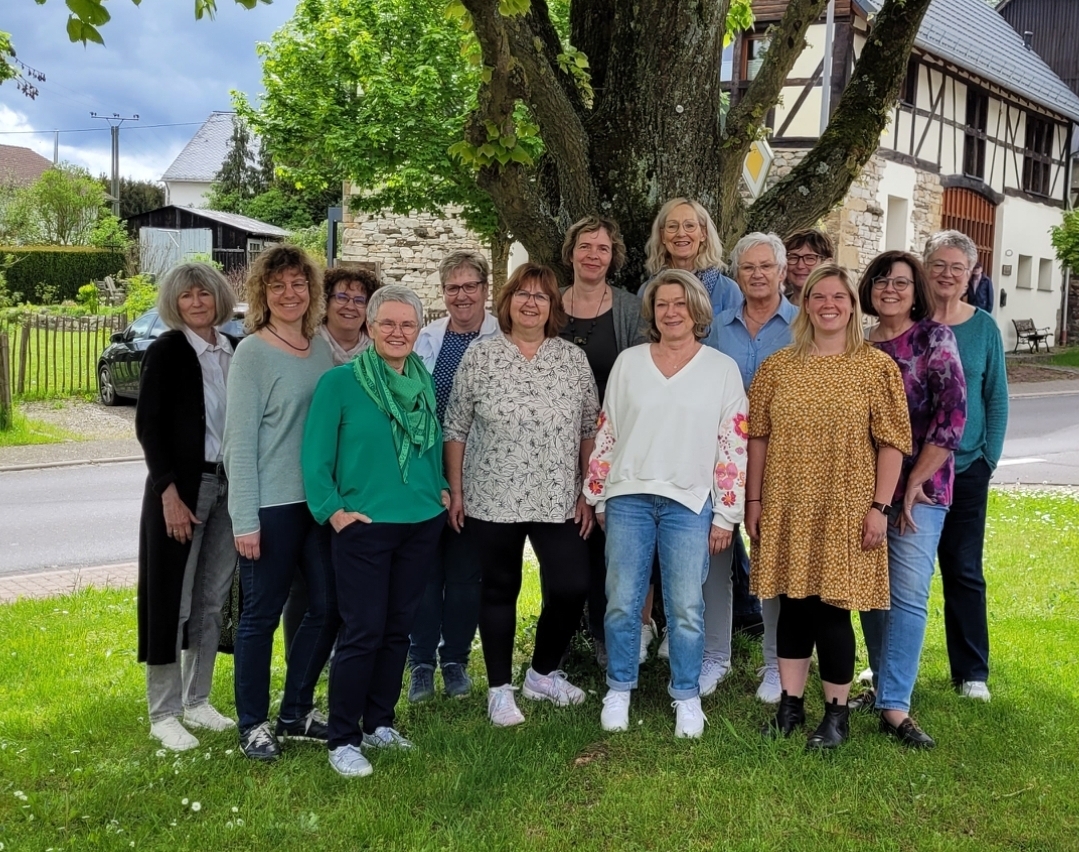 Gruppenbild Chor Man sieht die Mitgleider des Chrores auf einer Wiese stehen, im Hintergrund ist ein Baum und ein Fachwerkhaus zu sehen