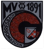Das Wappen hat einen grauen Hintergrund, im oberen Teil Steht MV 1891, darunter befindet sich ein roter Kreis mit einem schwarzen Punkt, links um den Kreis ist der Schriftzug Niederwörresbach zu lesen, rechts davon ist noch das Wappenn von Niederwörresbach zu sehen