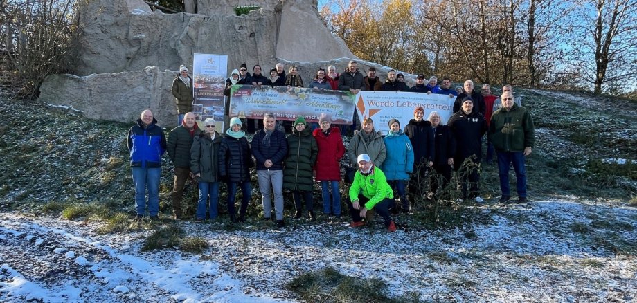 Gruppe von Personen mit Bannern vor einer Ruine inmitten von Wald, Wiesen bedeckt mit Schnee